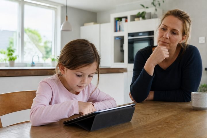 Kind am Tablet, Mutter schaut besorgt zu